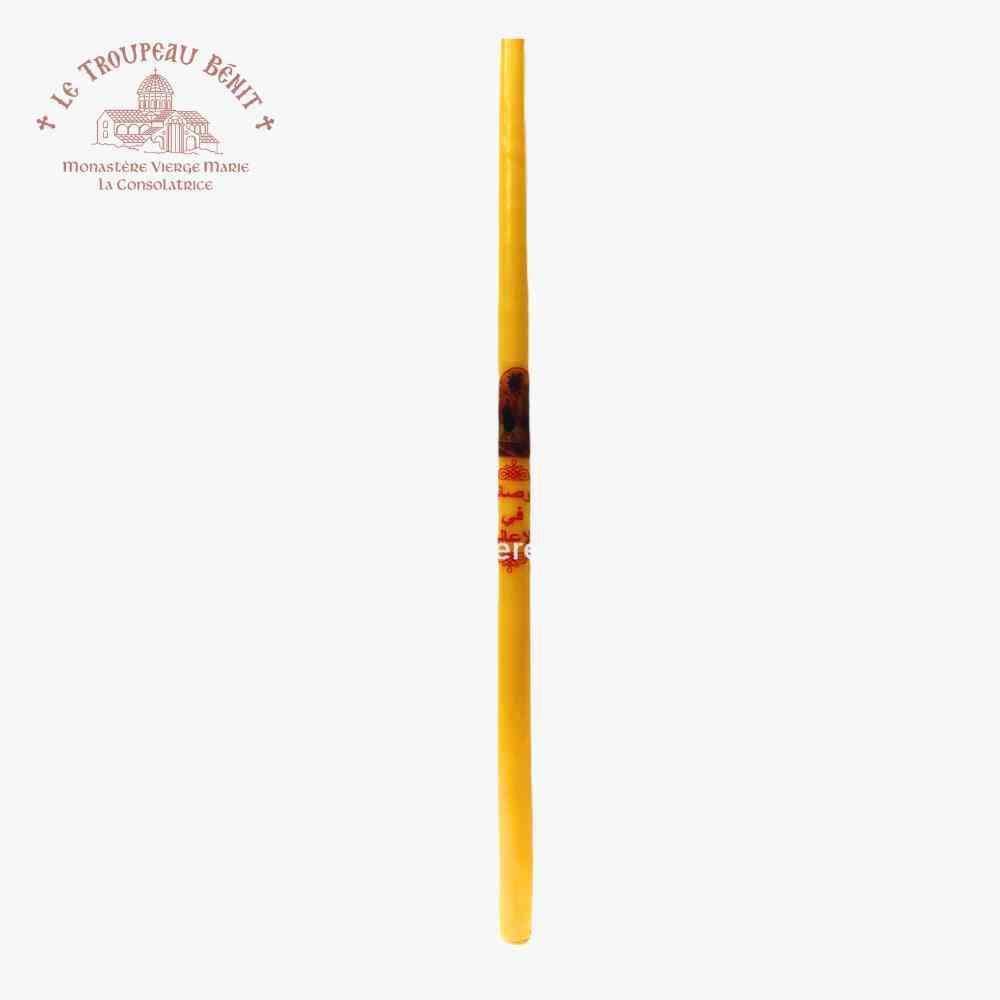 Yellow candle with Arabic text 'Blessed is He who comes in the name of the Lord' on a white background featuring 'Le Troupeau Benit' logo 