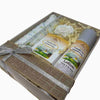 Set of skincare products including goat milk lotion, soap bar and a cotton scrubby in a decorative box with a bow.