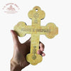 Hand holding a decorative cross with engraved text and symbols on a white background with "Troupeau Benit" logo branding