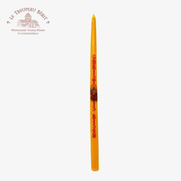 Tall yellow candle with red text 'Christ is risen' in English on a white background, featuring Le Troupeau Benit logo.