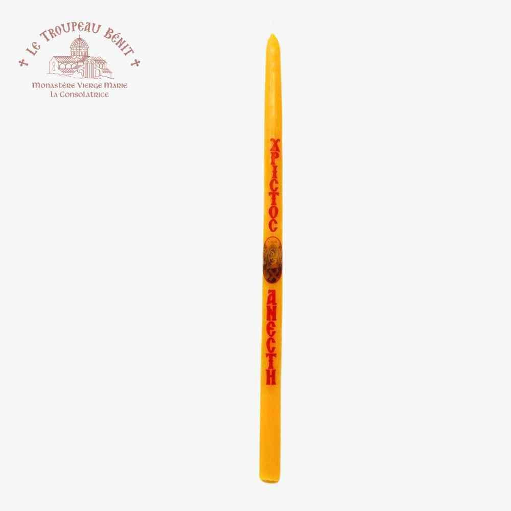 Yellow candle with red text in Greek on a white background, featuring the brand 'Le Troupeau Benit'.