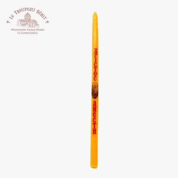 Yellow candle with red text in Greek on a white background, featuring the brand 'Le Troupeau Benit'.