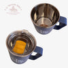 Two blue mugs with handles, one empty and one containing a yellow object, on a white background.