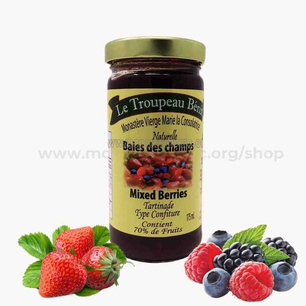Jar of mixed berries jam with a label Le Troupeau Benit and surrounding berries on a white background