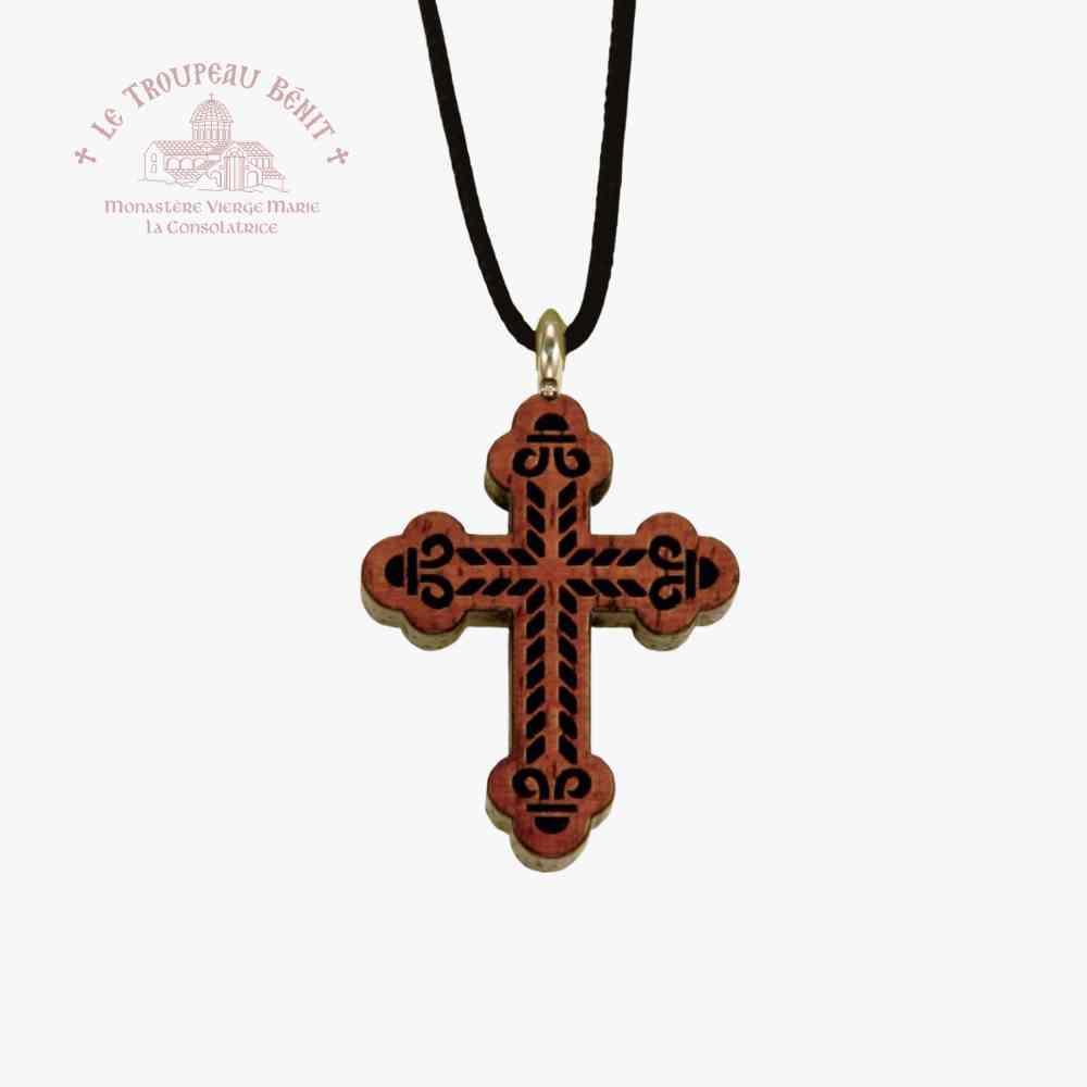 Wooden cross pendant with decorative patterns on a black cord against a white background with 