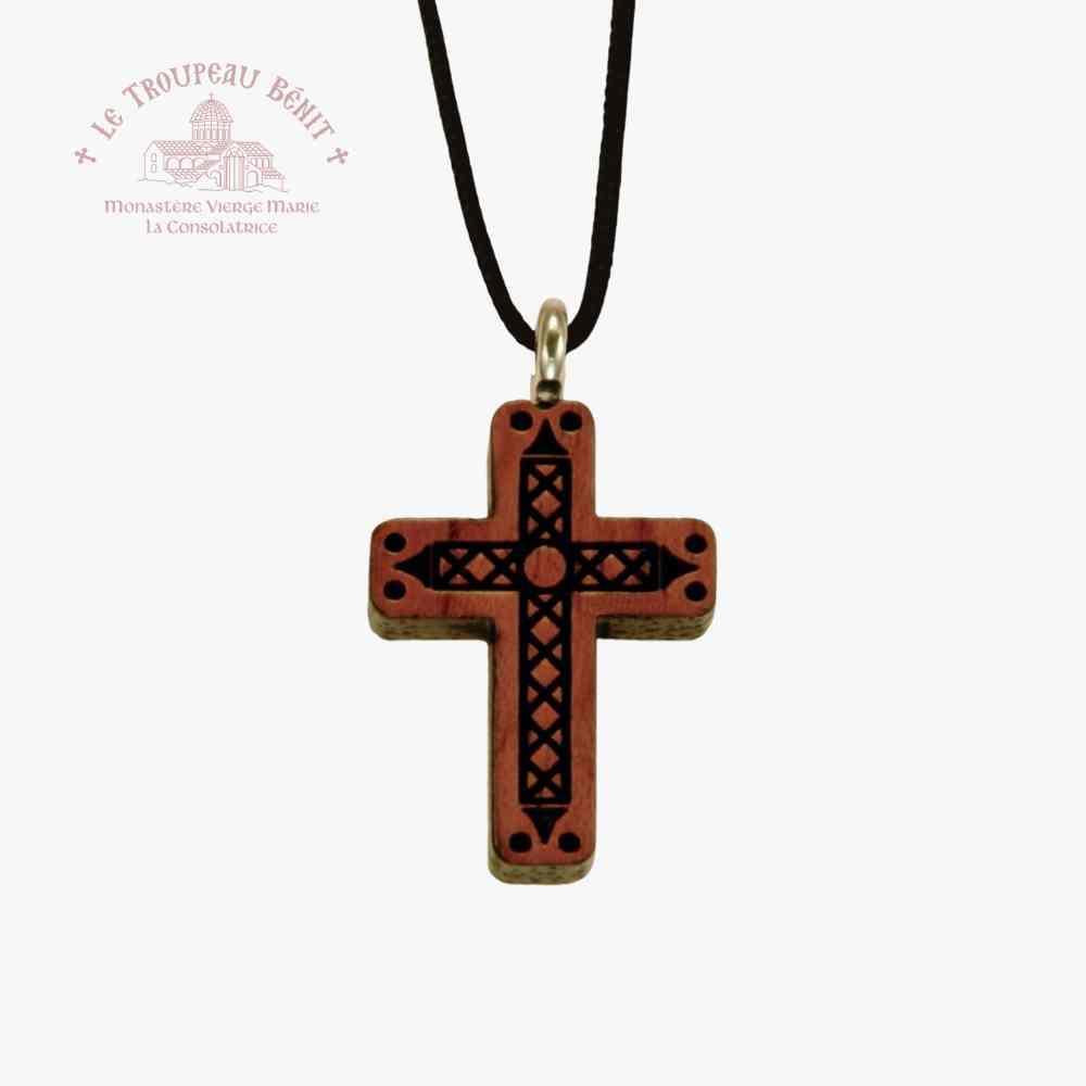 Wooden cross pendant with decorative patterns on a black cord against a white background with 