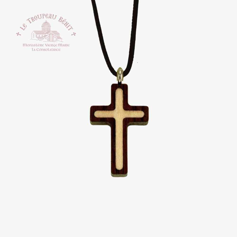 Wooden cross pendant on a black cord with Le Troupeau Bénit logo in the corner.
