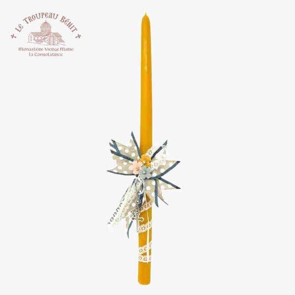 Decorative yellow Paschal candle with floral arrangement on a white background, featuring Le Troupeau Bénit logo.
