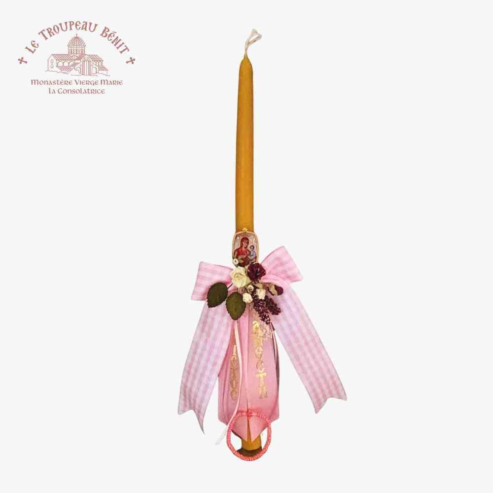 Decorative candle with a pink bow and floral arrangement on a white background, featuring the Le Troupeau Bénit logo.