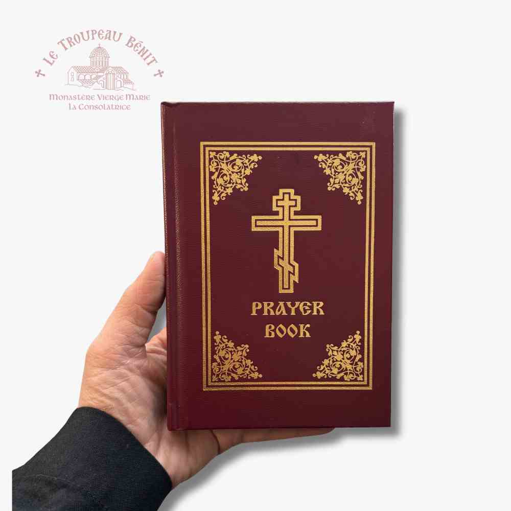 Red prayer book with gold cross and text held by a hand on a white background with 'Troupeau Benit' logo branding