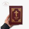Red prayer book with gold cross and text held by a hand on a white background with 'Troupeau Benit' logo branding