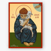 A religious icon painting of Saint Spyridon holding a white lamb, framed by a red border on a light gray background. The icon features a gold background, dark blue robes, and an olive green base.